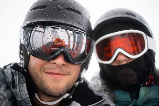 Selfie photo of a dad and daughter on the winter holiday. They are wearing ski equipment.