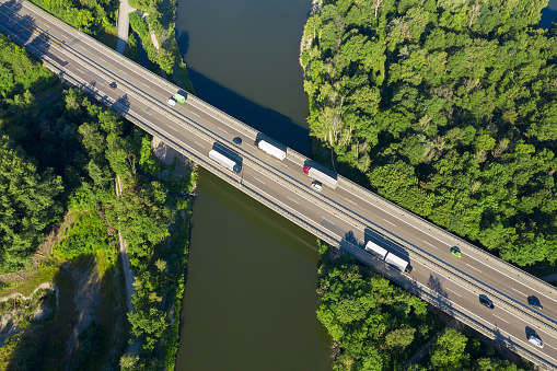 Trucks and cars on highway bridge over river, aerial view, Germany.