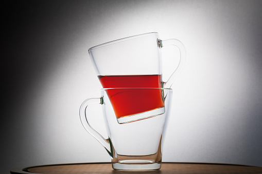 Glass mugs with tea, one inside the other, still life on a white background. Close-up