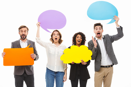 Portrait of a group of cheerful multiracial business people holding empty speech bubbles isolated over white background