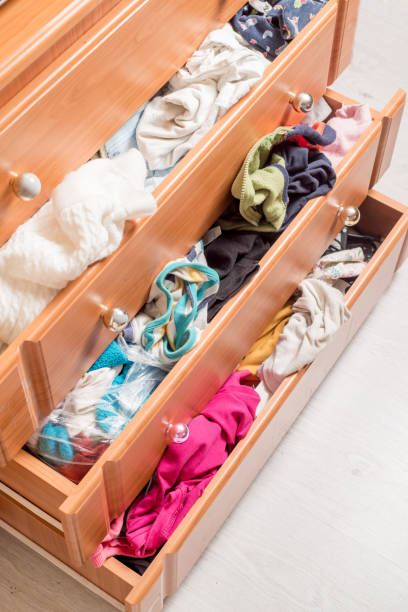 istock open chest drawers with sticking out randomly clothes.View from above 1306678100
