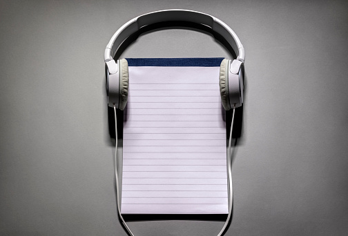 Headphones with blank notebook or notepad background with copy space for playlist or podcast