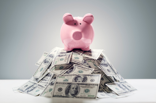 Piggy bank on pile of money concept for business finance, investment, saving or retirement fund