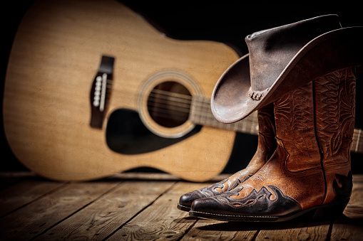 Country music festival live concert with acoustic guitar, cowboy hat and boots background