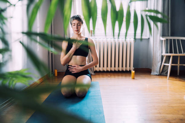 Breathing Exsercise Young woman enjoys the peace and relaxation of deep breath in the comfort and safety of her own home. Part of a regular routine, or the new normal of pandemic life during the Coronavirus inhaling stock pictures, royalty-free photos & images