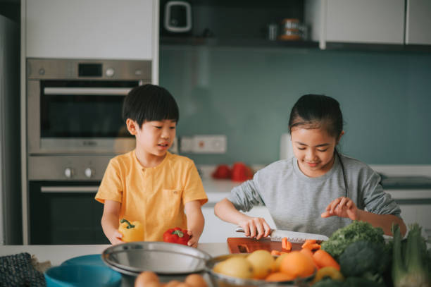 istock asian chinese sibling brother sister playing in kitchen cutting fruit 1306690021