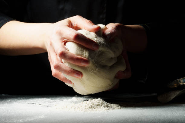istock Dough preparation process on a dark. female hands in a black jacket knead the dough. 1306691782