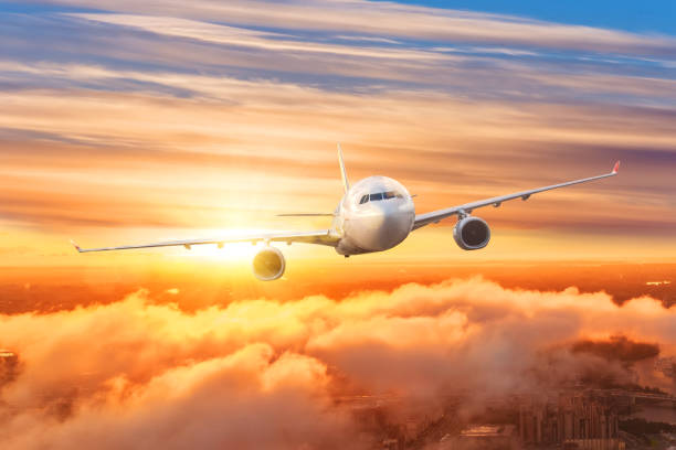 istock Airplane above the clouds in the sky at sunrise. 1306692486