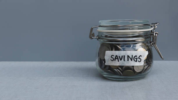 istock Savings concept. A jar of coins with text label on a grey background with copy space. 1306692913
