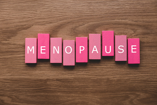 Un bloque de madera rosa con un texto de menopausia sobre fondo de madera. photo
