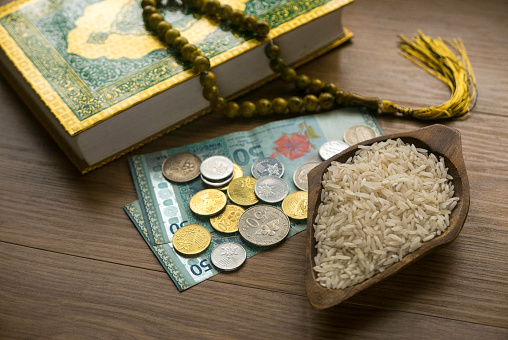 Concepto de zakat en la religión islámica. Enfoque selectivo del dinero, arroz, Corán y cuentas de oración sobre fondo de madera. photo