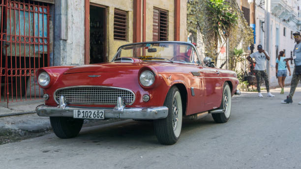 Havana, Cuba-December 2017: Authentic view and atmosphere on the streets of Havana. Cuban car driving true the neighbourhood filled up with local people and colonial residences in the background.