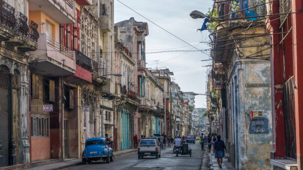 Authentic view and atmosphere on the streets of Havana. Havana, Cuba-December 2017: Authentic view and atmosphere on the streets of Havana. Cuban car driving true the neighbourhood filled up with local people and colonial residences in the background. driveway colonial style house residential structure stock pictures, royalty-free photos & images