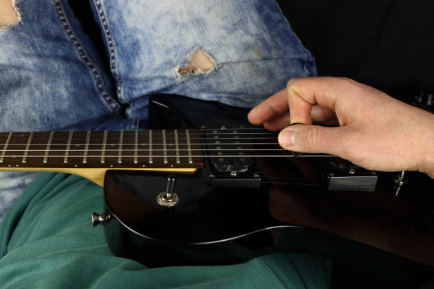 istock man sitting down plays a black electric guitar 1306697043