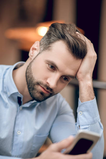 istock Young bearded man sitting at the table and looking anticipated 1306700022