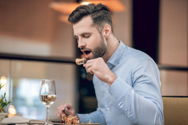istock Man eating seafood at the restaurant and looking involved 1306700058