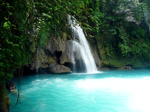 Close up of waterfall with rock and turquoise water from Kanchanaburi, Thailand.