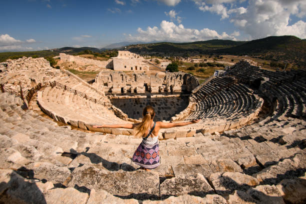 donna con le mani alzate alle rovine anfi-teatro dell'antica città licia patara. - women rear view one person arch foto e immagini stock