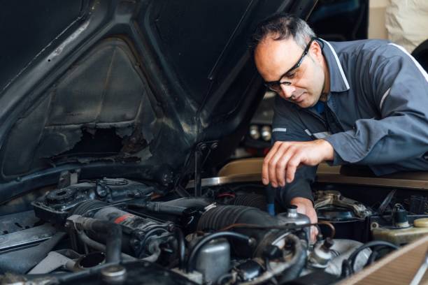 istock Portrait of a white mechanical man fixing a car engine failure. He's holding a tool from the workshop. Tightening screws by hand. Industrial concept 1306707729