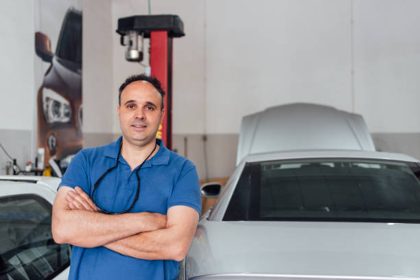 istock Happy car mechanic in his workshop poses standing in his elegant uniform. 1306707741