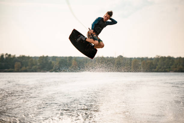 istock strong athletic guy actively jumps on wakeboard over the water 1306713742