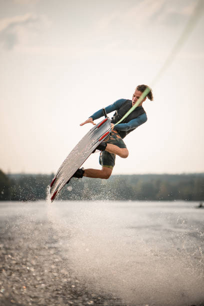 istock handsome man jumps spectacularly on wakeboard above the water with splashes 1306714376