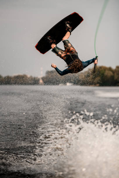 istock sportive guy doing extreme high jump on wakeboard over splashing river wave 1306714803