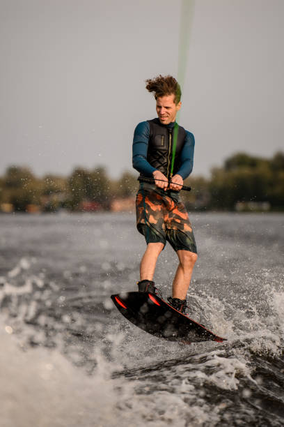 istock young guy wakeboarder holds rope in his hands and jumping on wave 1306715618