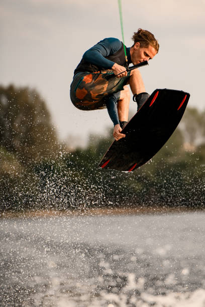 istock athletic man stands with bent knees on wakeboard and masterfully jumps over water 1306715648