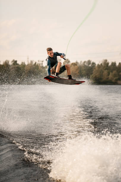 istock young sportive guy effectively jumps on wakeboard over the water 1306715665