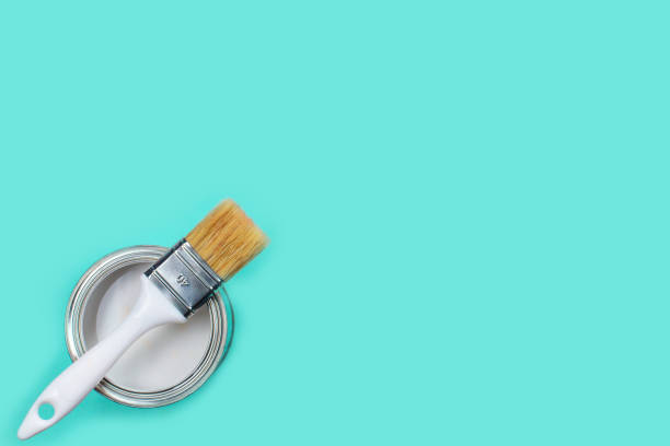 istock Open can with white paint and brush on light blue background, 1306715774