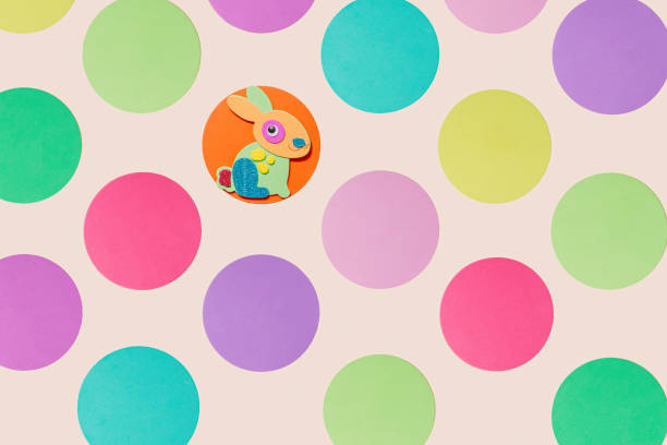 Eastern concept. A bunny decoration on round surface surrounded with other colorful circles. Top view on beige background.