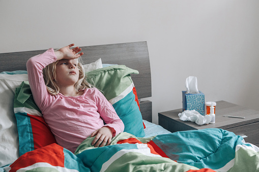 Sick ill tired Caucasian girl with fever lying in bed at home flu fever. Virus cold season flu cornavirus covid-19 illness. Medicine and health care concept.