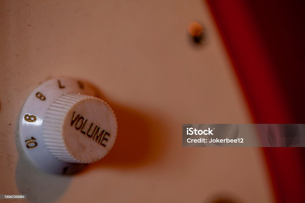 Vintage Volume adjustment knob on a red electric guitar. Volume adjustment knob on an red electric guitar.Shot with nice soft focus negative space.Volume Pot Adjusting Stock Photo