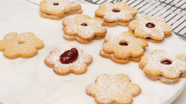 istock Flower shaped shortbread cookies filled with raspberry jam step by step recipe. Spreading a layer of raspberry jam on baked cookies 1306723954