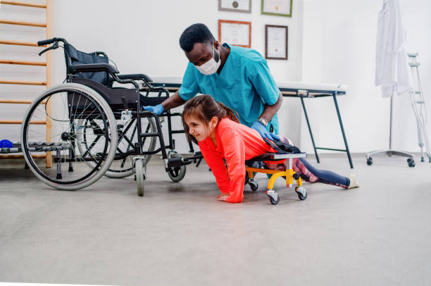Physical therapist helping girl to crawling with wheeled frame