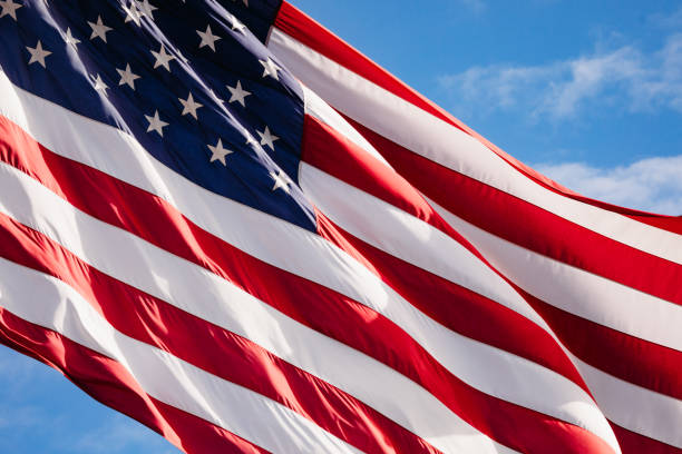 istock American Flag Blowing Against Vibrant Blue Sky 1306728168