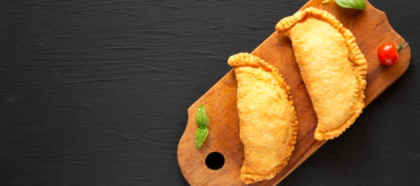 istock Homemade Deep Fried Italian Panzerotti Calzone on a rustic wooden board on a black surface, top view. Flat lay, overhead, from above. Space for text. 1306729419