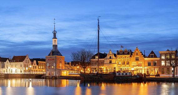 The Accijnstoren, excise tower, in Alkmaar, Netherlands, along a canal and 16th century houses in evening light