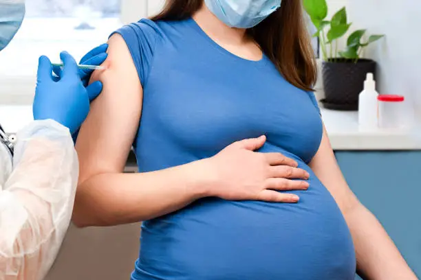 Photo of Pregnant Vaccination. Pregnant Woman In Face Mask Getting Vaccinated in Clinic. Doctor Giving Corona Virus Vaccine Injection Patient. Covid-19 Flu Protection. Selective focus.