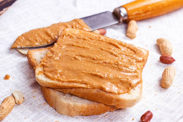istock Homemade toasts  for breakfast with fresh crunchy peanut butter and nuts on light textile background 1306738019