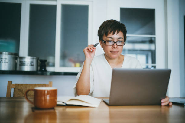 asian senior woman working on her home finance with laptop at home - retirement planning imagens e fotografias de stock