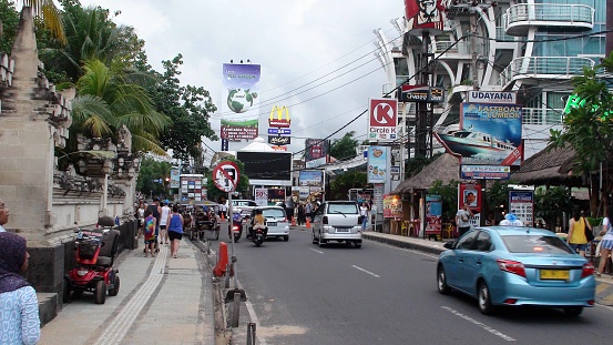 Kuta Downtown District In Bali Indonesia Southeast Asia, Building Exterior, Taxi, Road Traffic, Advertisement Sign, Retail Store, People Walking, Riding Motorcycle, Driving Vehicle Scenery During The Day