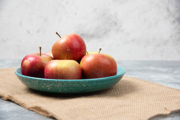 istock Blue bowl full of fresh apples on marble background 1306748814