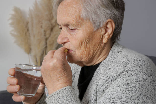 istock Elderly woman taking pills at home 1306749000