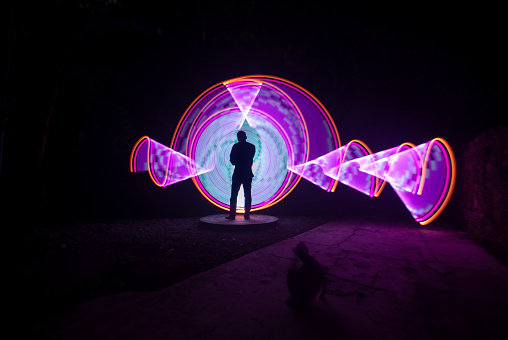 One person standing alone against red and white circle light painting as the backdrop