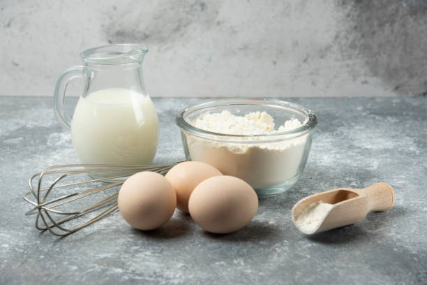 istock Flour, eggs, milk and whisker on marble background 1306751397