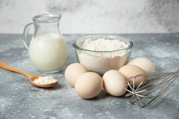 istock Bowl of flour, eggs and milk on marble background 1306760225