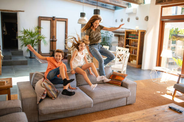 istock Active Mother and Young Children Jumping Over Back of Sofa 1306762535