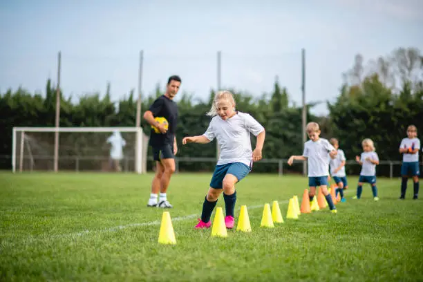 Photo of Coach Watching Action of Girl Footballer Doing Agility Drill